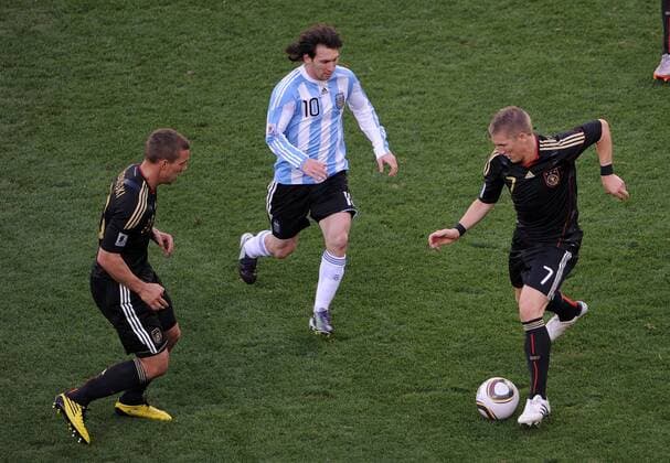 FUSSBALL WM 2010 VIERTELFINALE 02.07.2010 ARGENTINIEN - DEUTSCHLAND Lukas PODOLSKI (li) und Bastian SCHWEINSTEIGER (re, beide Deutschland) gegen Lionel MESSI (Mitte, Argentinien)