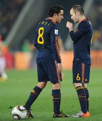 Xavi Hernandez (L) of Spain talks with teammate Andres Iniesta before taking a freekick during the 2010 World Cup quarterfinal soccer match against Paraguay at Ellis Park stadium in Johannesburg on July 3, 2010. 
