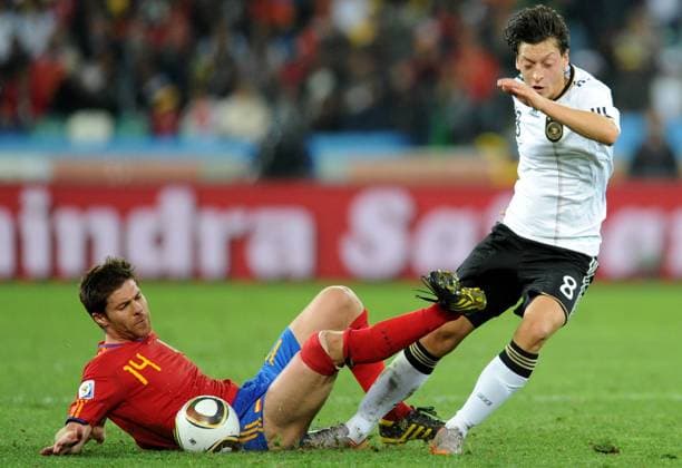 Spain s Xabi Alonso (L) vies with Germany s Mesut Oezil during the 2010 World Cup semifinal match in Durban, July 7, 2010. 