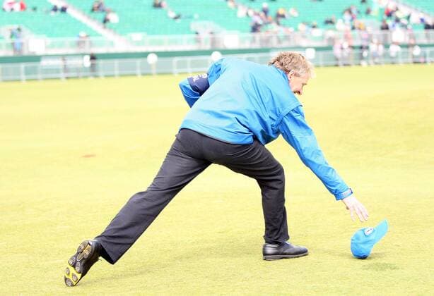 Golf - The British Open - St Andrews Due to high winds causing the balls to oscillate play has been suspended during the second day of the open. Picture is a course official chasing his hat after a gust of wind had blown it away on the first fairway.  o0 Wind Kurios