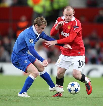 Manchester United (red) vs Glasgow Rangers (blue) - Rangers Steven Davies tackles Wayne Rooney of Manchester United during the Manchester United vs Glasgow Rangers, Group C, Champions League match. Old Trafford.  101592558 1015