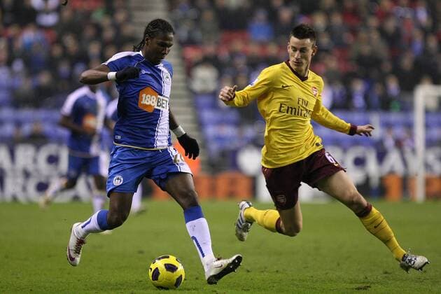 Football - Premier League - Wigan Athletic (blue) vs. Arsenal FC (yellow): Wigan s Hugo Rodallega and Arsenal s Laurent Koscielny in action at the DW Stadium 