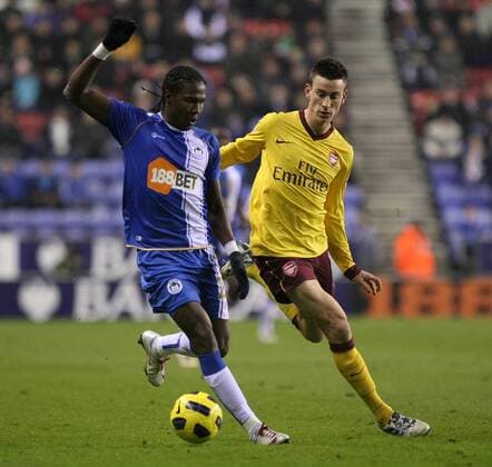 Football - Premier League - Wigan Athletic (blue) vs. Arsenal FC (yellow): Wigan s Hugo Rodallega and Arsenal s Laurent Koscielny in action at the DW Stadium 