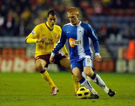 Ben Watson of Wigan Athletic and Marouane Chamakh of Arsenal - Barclays Premier League, Wigan Athletic (blue) vs Arsenal FC (yellow) 29th December, 2010 EDITORIAL USE ONLY. No use with unauthorised audio, video, data, fixture lists, club league logos or live services. Online in-match use limited to 120 images, no video emulation. No use in betting, games or single club league player publications.