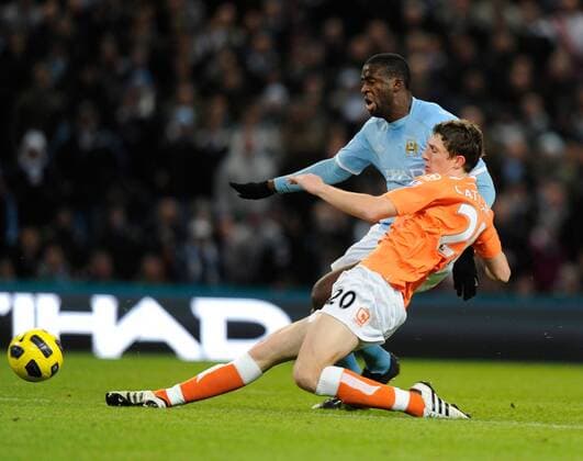 Craig Cathcart of Blackpool takes the ball off Yaya Toure of Manchester City (blue) as he was clear through on goal --- Barclays Premier League 2010 2011 - Manchester City (blue) vs FC Blackpool (orange), 1st January, 2011 EDITORIAL USE ONLY. No use with unauthorised audio, video, data, fixture lists, club league logos or live services. Online in-match use limited to 120 images, no video emulation. No use in betting, games or single club league player publications.