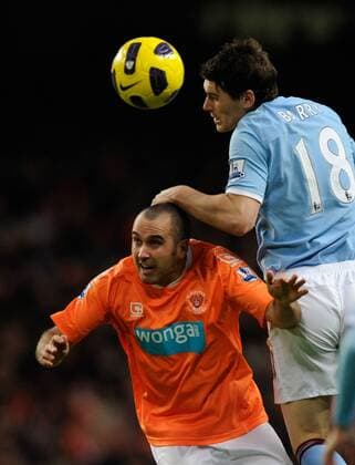 Gary Taylor Fletcher of Blackpool challenged by Gareth Barry of Manchester City (blue) --- Barclays Premier League 2010 2011 - Manchester City (blue) vs FC Blackpool (orange), 1st January, 2011 EDITORIAL USE ONLY. No use with unauthorised audio, video, data, fixture lists, club league logos or live services. Online in-match use limited to 120 images, no video emulation. No use in betting, games or single club league player publications.