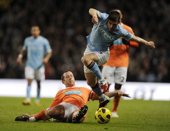 James Milner of Manchester City (blue) skips over the tackle made by Charlie Adam of Blackpool --- Barclays Premier League 2010 2011 - Manchester City (blue) vs FC Blackpool (orange), 1st January, 2011 EDITORIAL USE ONLY. No use with unauthorised audio, video, data, fixture lists, club league logos or live services. Online in-match use limited to 120 images, no video emulation. No use in betting, games or single club league player publications.