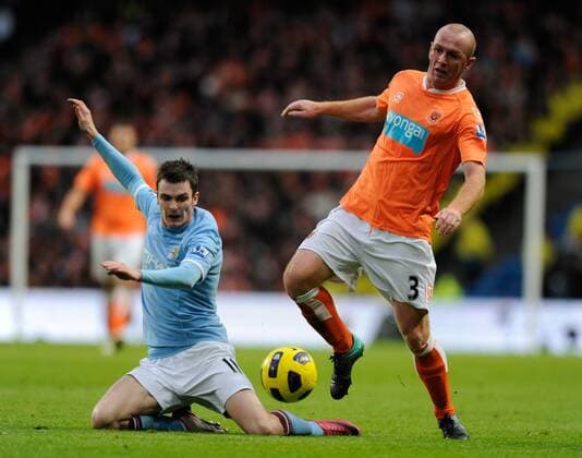 Adam Johnson of Manchester City (blue) tackles Stephen Crainey of Blackpool --- Barclays Premier League 2010 2011 - Manchester City (blue) vs FC Blackpool (orange), 1st January, 2011 EDITORIAL USE ONLY. No use with unauthorised audio, video, data, fixture lists, club league logos or live services. Online in-match use limited to 120 images, no video emulation. No use in betting, games or single club league player publications.