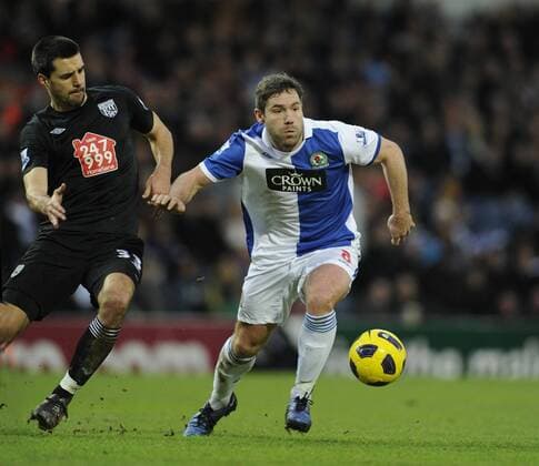 David Dunn of Blackburn Rovers (blue) skips past the challenge by Paul Scharner of West Bromwich Albion (black) Barclays Premier League Blackburn Rovers v West Bromwich Albion 23rd January, 2011 EDITORIAL USE ONLY. No use with unauthorised audio, video, data, fixture lists, club league logos or live services. Online in-match use limited to 120 images, no video emulation. No use in betting, games or single club league player publications.