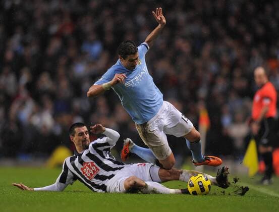 Paul Scharner of West Bromwich Albion (L) tackles Aleksander Kolarov of Manchester City --- Manchester City vs. West Bromwich Albion EDITORIAL USE ONLY. No use with unauthorised audio, video, data, fixture lists, club league logos or live services. Online in-match use limited to 120 images, no video emulation. No use in betting, games or single club league player publications. o0 Aufmacher Kampf Einsatz Grätsche, grätschen, Tackling Härte