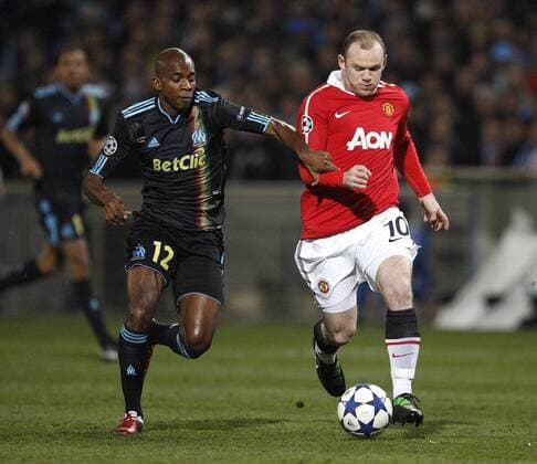 Wayne Rooney of Manchester United holds off Charles Kabore of Marseille --- Champions League Round of 16 First Leg - Olympique Marseille (blue) vs. Manchester United ManU (red) --- EDITORIAL USE ONLY. No use with unauthorised audio, video, data, fixture lists, club league logos or live services. Online in-match use limited to 120 images, no video emulation. No use in betting, games or single club league player publications.