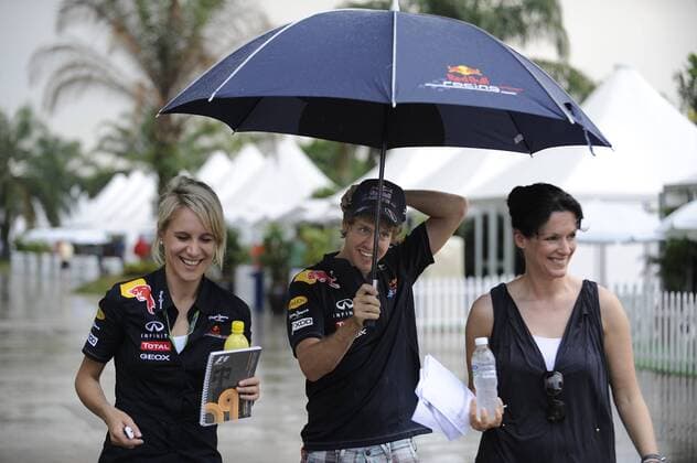 Sebastian VETTEL (GER),Red Bull Racing ,Halbfigur,halbe Figur,geht mit einem Regenschirm waehrend des taeglichen Regenschauers durch das Fahrerlager,Paddock und schuetzt seine Pressesprecherin Britta Röske (li) und Sky Reporterin Tanja Bauer (re) vor dem Regen. Formel 1:GP von Malaysia Sepang Circuit Kuala Lumpur,Saison2011,