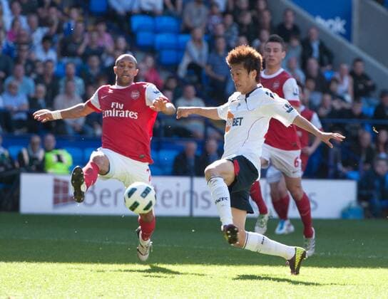 Chung Yong Lee (C) of Bolton Wanderers has a shot on goal despite the attentions of Abou Diaby (L) of Arsenal Barclays Premier League; Bolton Wanderers vs Arsenal FC London 24th April, 2011 EDITORIAL USE ONLY. No use with unauthorised audio, video, data, fixture lists, club league logos or live services. Online in-match use limited to 120 images, no video emulation. No use in betting, games or single club league player publications.