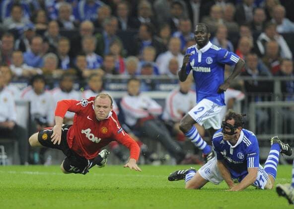 Wayne Rooney of Manchester United is brought down by Christoph Metzelder of FC Schalke 04 - Champions League SemiFinal 1st leg - FC Schalke 04 (blue) vs Manchester United (ManU) - EDITORIAL USE ONLY. No use with unauthorised audio, video, data, fixture lists, club league logos or live services. Online in-match use limited to 120 images, no video emulation. No use in betting, games or single club league player publications.