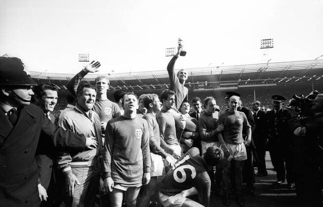 Fußball, WM 1966, Finale in Wembley, England - Deutschland 4-2 n.V. Weltmeister England 1966, v.li.: Nationaltrainer Harold Shepherdson, Jack Charlton, Nobby Stiles, Alan Ball, Geoff Hurst, Bobby Moore mit dem Coupe Jules Rimet, daneben George Cohen (2.v.re.), Bobby Charlton (re.) und Martin Peters (16) Jubel, Freude Sieg Weltmeister Siegerehrung Pokal Trophäe Objekte Trainer