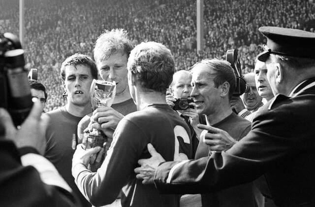 Fußball, WM 1966, Finale in Wembley, England - Deutschland 4-2 n.V. Bobby Moore (6) mit dem Coupe Jules Rimet nach dem Sieg im Finale der WM 1966, daneben v.li.: Geoff Hurst, Jack Charlton und Bobby Charlton (alle England) Jubel, Freude Sieg Weltmeister Siegerehrung Nationaltrikot Fotograf, Sportfotograf