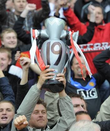 A Manchester United fan holds up a inflatable Premier League trophy with 19 on it - Premier League - Manchester United (ManU) - EDITORIAL USE ONLY. No use with unauthorised audio, video, data, fixture lists, club league logos or live services. Online in-match use limited to 120 images, no video emulation. No use in betting, games or single club league player publications.