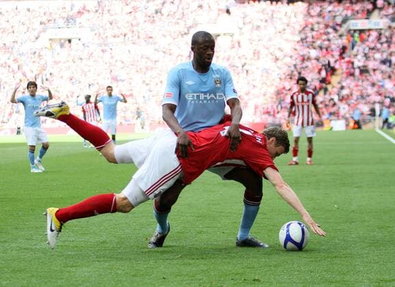 Manchester Citys Yaya Toure holds Stokes Robert Huth in the air EON FA Cup Final Manchester City (blue) v Stoke City (red white) 14th May, 2011 EDITORIAL USE ONLY. No use with unauthorised audio, video, data, fixture lists, club league logos or live services. Online in-match use limited to 120 images, no video emulation. No use in betting, games or single club league player publications.