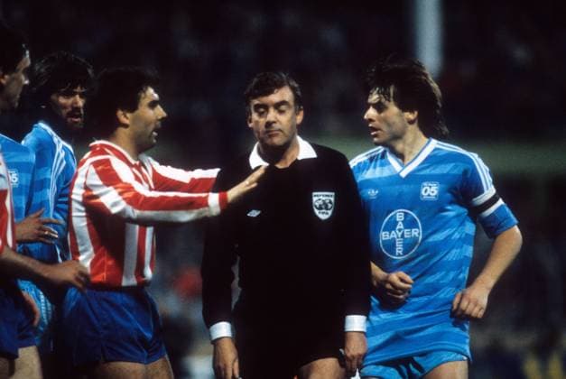 Europacup der Pokalsieger 1985 1986 - Halbfinale - Rückspiel in Krefeld - Bayer 05 Uerdingen - Atletico Madrid 2:3 - Julio Prieto (Atletico, 3.v.li.), Friedhelm Funkel (2.v.li.) und Matthias Herget (re., beide Uerdingen) belagern Schiedsrichter Neil Midgeley (England) - DEUTSCHSPRACHIGE SPORTZEITSCHRIFTEN UND -ZEITUNGEN NUR NACH RÜCKSPRACHE Aktion