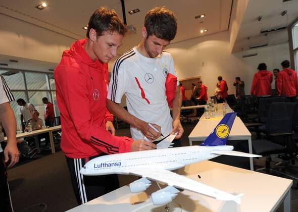 Benedikt Höwedes, Thomas Müller unterschreibt auf einen Flugzeug Modell Die deutsche Fussball-Nationalmannschaft beim Lufthansa Flight Training Center am Flughafen Frankfurt. Fussball: Vorbereitung der deutschen Fussball Nationalmannschaft der Männer in Frankfurt Main, 31.05.2011.