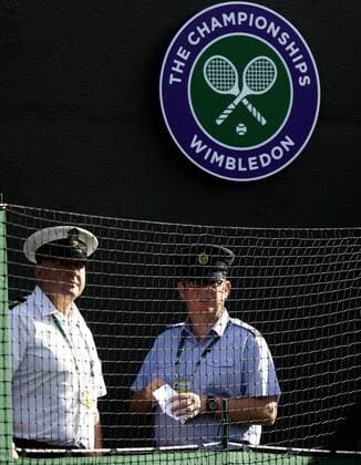 Wimbledon Championships 2011, AELTC, London, ITF Grand Slam Tennis Tournament . zwei uniformierte Männer stehen hinter einem Netz und unter dem Wimbledon Logo am Platzrand,Hochformat, , o0 Sicherheit Logo Emblem Symbol o00 Schriftzug