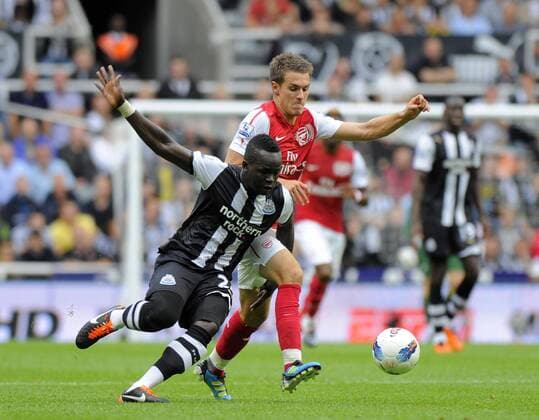 Cheik Tiote of Newcastle United tangles with Aaron Ramsey of Arsenal (R) during the Premier League football match between Newcastle United and Arsenal FC London on 13 August, 2011, at St. James Park, Newcastle upon Tyne, England. Barclays Premier League 2011 EDITORIAL USE ONLY. No use with unauthorised audio, video, data, fixture lists, club league logos or live services. Online in-match use limited to 120 images, no video emulation. No use in betting, games or single club league player publications.