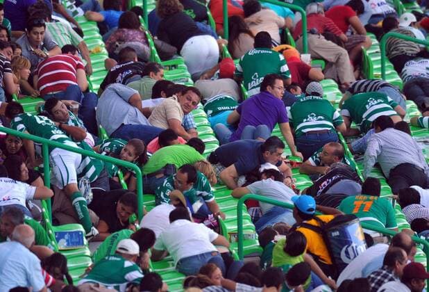Fans protect themselves after hearing a gunfight outside the Corona s stadium, in Torreon, northern Mexico, on Aug. 20, 2011. The Mexican first division match between Santos and Morelia was suspended after an armed group attacked a police patrol outside the stadium, authorities said -  o00 Gesellschaft
