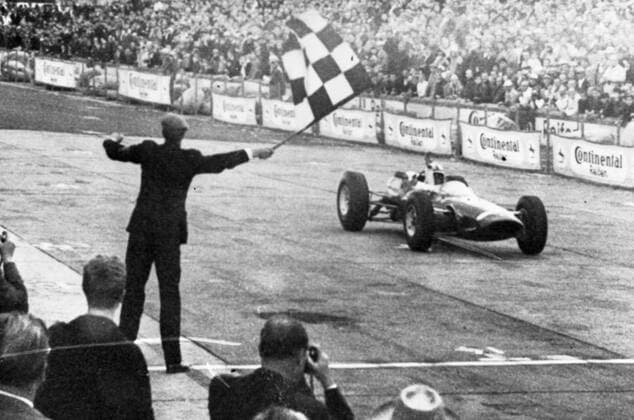 John Surtees roars across the finish line in his Ferrari to win the German Grand Prix at Adenau. 2 August 1964 UnitedArchives1244323