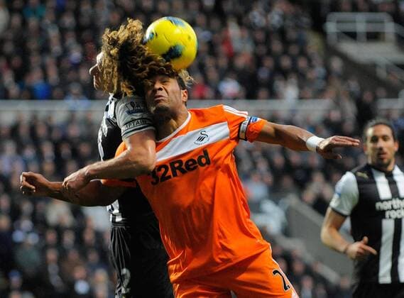 Fabricio Coloccini of Newcastle United (L) go head to head for the ball with Ashley Williams of Swansea City FC during the Premier League football match between Newcastle United and Swansea City on 17 December 2011, at Sports Direct Arena, Newcastle upon Tyne, England. EDITORIAL USE ONLY. No use with unauthorised audio, video, data, fixture lists, club league logos or live services. Online in-match use limited to 120 images, no video emulation. No use in betting, games or single club league player publications.