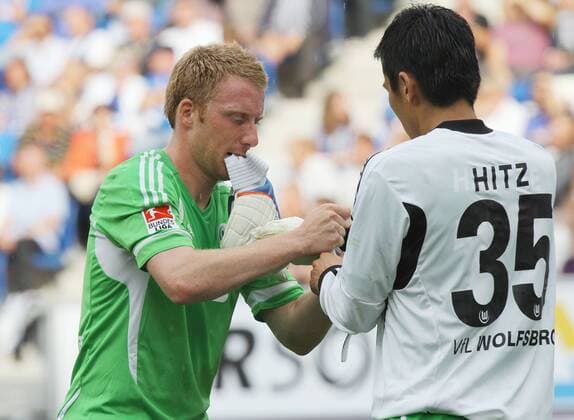 Fussball Bundesliga TSG 1899 Hoffenheim vs. VfL Wolfsburg links: Patrick Ochs hilft seinem Mitspieler Makoto Hasebe ( Wolfsburg ) beim Anziehen der Torwarthandschuhe.Dieser muss nach der Roten Karte von Torhüter Marwin Hitz ins Tor
