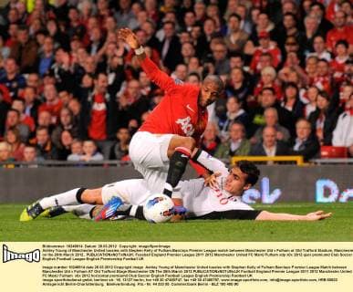 Ashley Young of Manchester United tussles with Stephen Kelly of Fulham.Barclays Premier League match between Manchester Utd v Fulham at Old Trafford Stadium, Manchester on the 26th March 2012.. EDITORIAL USE ONLY. No use with unauthorised audio, video, data, fixture lists, club league logos or live services. Online in-match use limited to 120 images, no video emulation. No use in betting, games or single club league player publications.