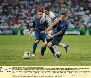 Football - UEFA Euro 2012 - France vs. England England s Steven Gerrard goes down under the challenge of Mathieu Debuchy and Yahan Cabaye of France at the Donbass Arena, Donetsk, Ukraine 