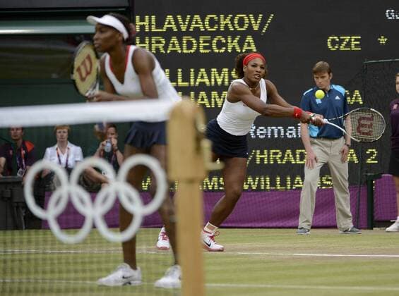 Serena Williams of the United States (R) returns a shot as her sister Venus watches their opponents, Andrea Hlavackova and Lucie Hradecka of the Czech Republic, during the Women s Doubles Gold Medal tennis match at the London 2012 Summer Olympics on August 5, 2012 in Wimbledon, London.  OLY20120805456