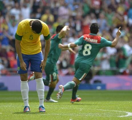 Sandro of Brazil (L) reacts as Oribe Peralta (C) and Marco Fabian of Mexico celebrate Peralta s goal during the first half of the Gold Medal Football Match at the London 2012 Summer Olympics on August 11, 2012 at Wembley Stadium, London.  OLY20120811402
