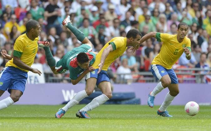 Forward Oribe Peralta of Mexico (L-R) falls over midfielder Sandro of Brazil as defender Romulo of Brazil looks for the ball during the first half of the Gold Medal Football Match at the London 2012 Summer Olympics on August 11, 2012 at Wembley Stadium, London.  OLY20120811407