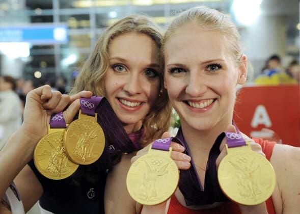 ITAR-TASS: MOSCOW, RUSSIA. AUGUST 14, 2012. Russia s synchronised swimmers Natalya Ishchenko (L) and Svetlana Romashina show their gold medals upon the arrival at Moscow s Sheremetyevo International Airport.  RE105DE9