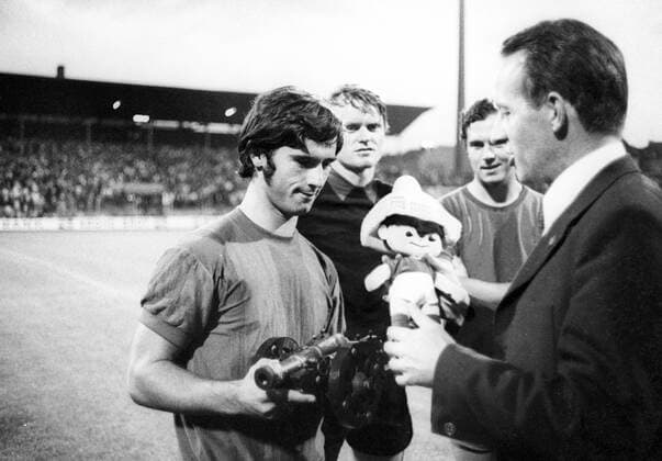 Gerd Müller (li.) erhält die Torjägerkanone sowie das Maskottchen der WM 1970 in Mexiko, dahinter Torwart Sepp Maier (2.v.li.) und Franz Beckenbauer (alle FC Bayern München)