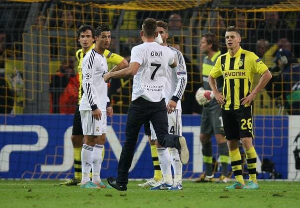 24.10.2012, Dortmund, Fussball, Champions-League, 3. Spieltag, Borussia Dortmund - Real Madrid. Ein Flitzer mit einem T-Shirt mit der Aufschrift GOLF 7 VERKAUFSSTART AB NOVEMBER läuft auf Cristiano Ronaldo (Madrid) und Sergio Ramos (Madrid) zu. Rechts Lukasz Piszczek (Dortmund).