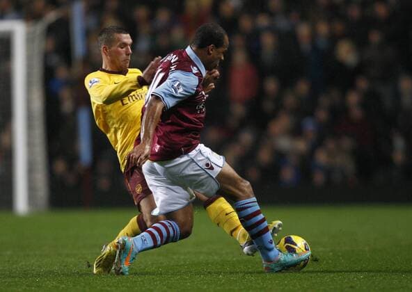 Football -Premiership - Aston Villa vs FC Arsenal London- Arsenal s Lukas Podolski and Aston Villa s Gabriel Agbonlahor battle for the ball at Villa Park. 