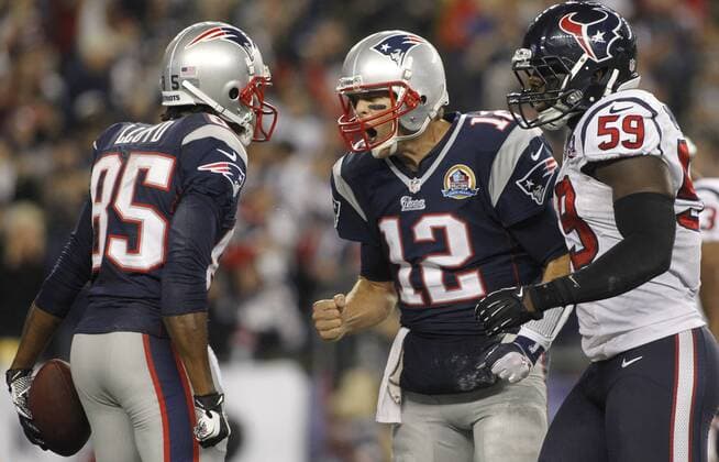 New England Patriots quarterback Tom Brady (12) celebrates with wide receiver Brandon Lloyd (85) as Houston Texans linebacker Whitney Mercilus (59) walks past them after Brady connected with Lloyd on a 37-yard touchdown reception in the first quarter at Gillette Stadium in Foxborough, Massachusetts on December 10, 2012.  BOS2012121008