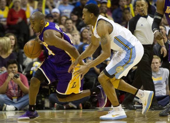 Los Angeles Lakers guard Kobe Bryant dribbles away from Denver Nuggets forward Andre Iguodala during the third quarter at the Pepsi Center on December 26, 2012 in Denver. The Nuggets stopped the Lakers winning streak with a 126-114 victory.  DEN2012122623