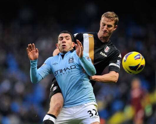 Carlos Tevez of Manchester City challenged by Brede Hangeland of Fulham FC - Barclays Premier League - Manchester City vs FC Fulham - Etihad Stadium - Manchester - 13 01 13 - Picture Simon Bellis Sportimage EDITORIAL USE ONLY. No use with unauthorised audio, video, data, fixture lists, club league logos or live services. Online in-match use limited to 120 images, no video emulation. No use in betting, games or single club league player publications.