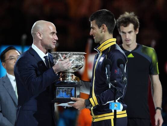Australian Open 2013, Melbourne Park,ITF Grand Slam Tennis Tournament,Herren Endspiel,Finale,Siegerehrung,Andre Agassi uebergibt den Pokal an den Sieger Novak Djokovic (SRB) im Hintergrund steht ein enttäuschter Finalist Andy Murray (GBR)