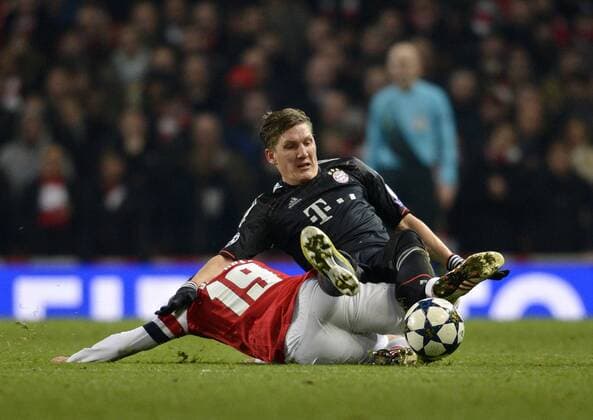 19.02.2013, Fussball Champions League: FC Arsenal London - FC Bayern München, im Emirates-Stadion London. Bastian Schweinsteiger (München) fällt über Santi Cazorla (Arsenal).