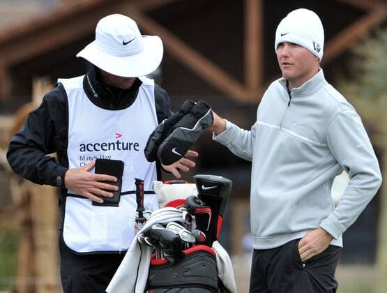 Russell Henley of the United States hands his mittens to his caddy at the tenth tee during the first round of the Accenture World Golf Championship at The Golf Club at Dove Mountain in Marana, Arizona February 20, 2013. Play has been suspended due to snow.  PXP2013022002