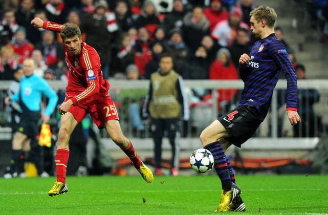 13. März 2013: München, Allianz Arena: Fussball UEFA Champions League, Achtelfinale: FC Bayern München - FC Arsenal London: Münchens Thomas Müller (rot) gegen Londons Per Mertesacker.