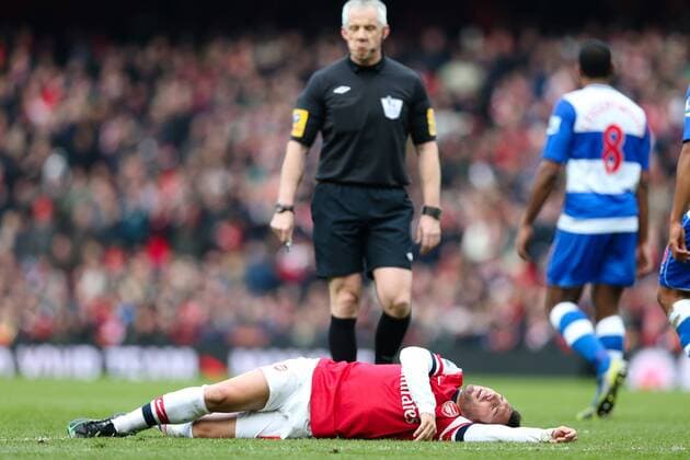 Football - 2012 2013 Premier League - Arsenal FC London - Reading FC; Santi Cazorla of Arsenal lies on the floor while referee Chris Foy stands over him at the Emirates Stadium 