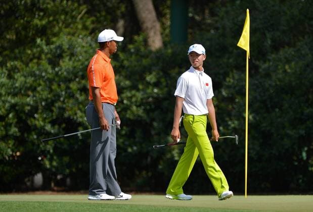 Tiger Woods talks to 14-year-old amateur Guan Tianlang of China as they walk on the 11th green during a practice round before the Master golf tournament at Augusta National Golf Club on April 8, 2013 in Augusta, Georgia.  AUG20130408362