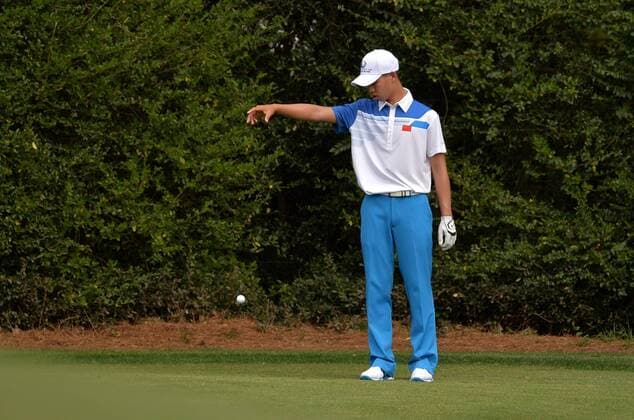 Guan Tianlang takes a drop after hitting his ball into the water on the 11th green during the first round of the Masters at Augusta National on April 11, 2013 in Augusta, Georgia.  AUG20130411379