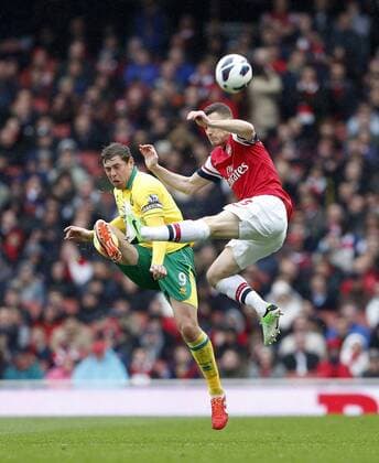 Arsenal s Thomas Vermaelen tussles with Norwich s Grant Holt.. FC Arsenal London vs Norwich City - Barclays Premier League - Emirates Stadium, London- 12 04 13 - EDITORIAL USE ONLY. No use with unauthorised audio, video, data, fixture lists, club league logos or live services. Online in-match use limited to 120 images, no video emulation. No use in betting, games or single club league player publications.
